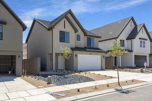 View of front facade featuring a garage, concrete driveway, and stucco siding