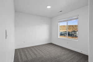 Unfurnished room with baseboards and dark colored carpet