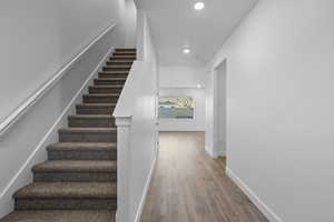 Stairs featuring wood finished floors and recessed lighting