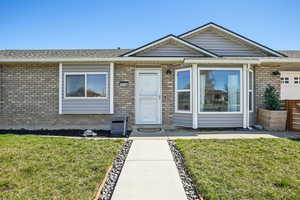 View of front of house featuring a front yard, roof with shingles, brick siding, and an attached garage