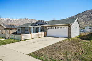 Single story home with a fenced front yard, a mountain view, a garage, concrete driveway, and brick siding