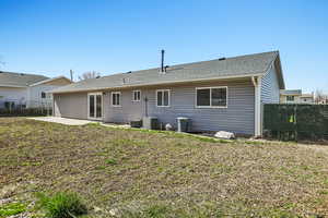 Rear view of property with a fenced backyard, a shingled roof, and a patio