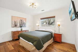 Bedroom with dark wood-type flooring and baseboards
