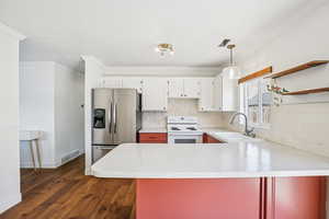 Kitchen with stainless steel fridge with ice dispenser, pendant lighting, electric range, a peninsula, and crown molding