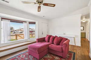 Living area featuring hardwood / wood-style floors, ceiling fan, ornamental molding, and a textured ceiling