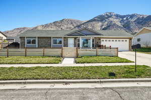 Ranch-style home featuring brick siding, a mountain view, a garage, driveway, and a shingled roof