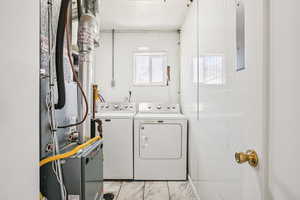 Laundry room featuring heating unit and washer and clothes dryer