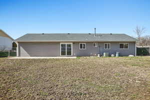 Rear view of house featuring a fenced backyard, a shingled roof, and a patio