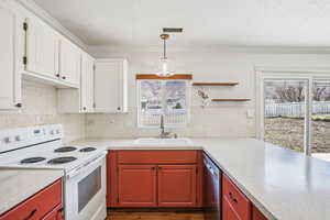 Kitchen with electric range, decorative light fixtures, dishwasher, two tone cabinetry, and backsplash