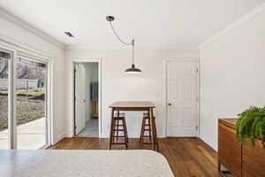 Dining space with dark wood finished floors and ornamental molding