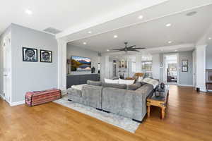 Living area featuring decorative columns, light wood-style flooring, a ceiling fan, and recessed lighting