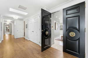 Hallway with light wood-style flooring and ornamental molding
