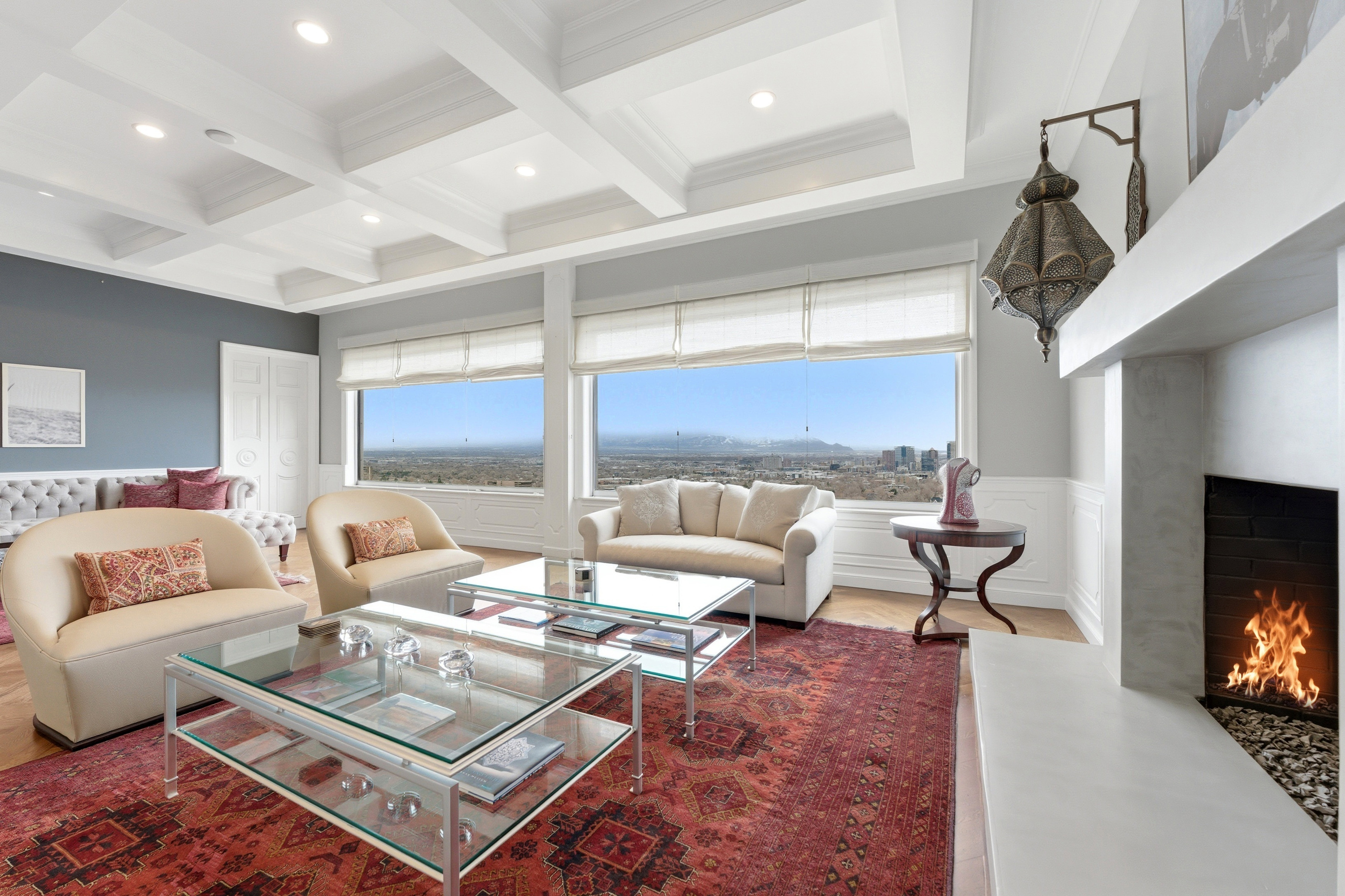 Living room with a premium fireplace, coffered ceiling, dark wood-style flooring, a wainscoted wall, and healthy amount of natural light