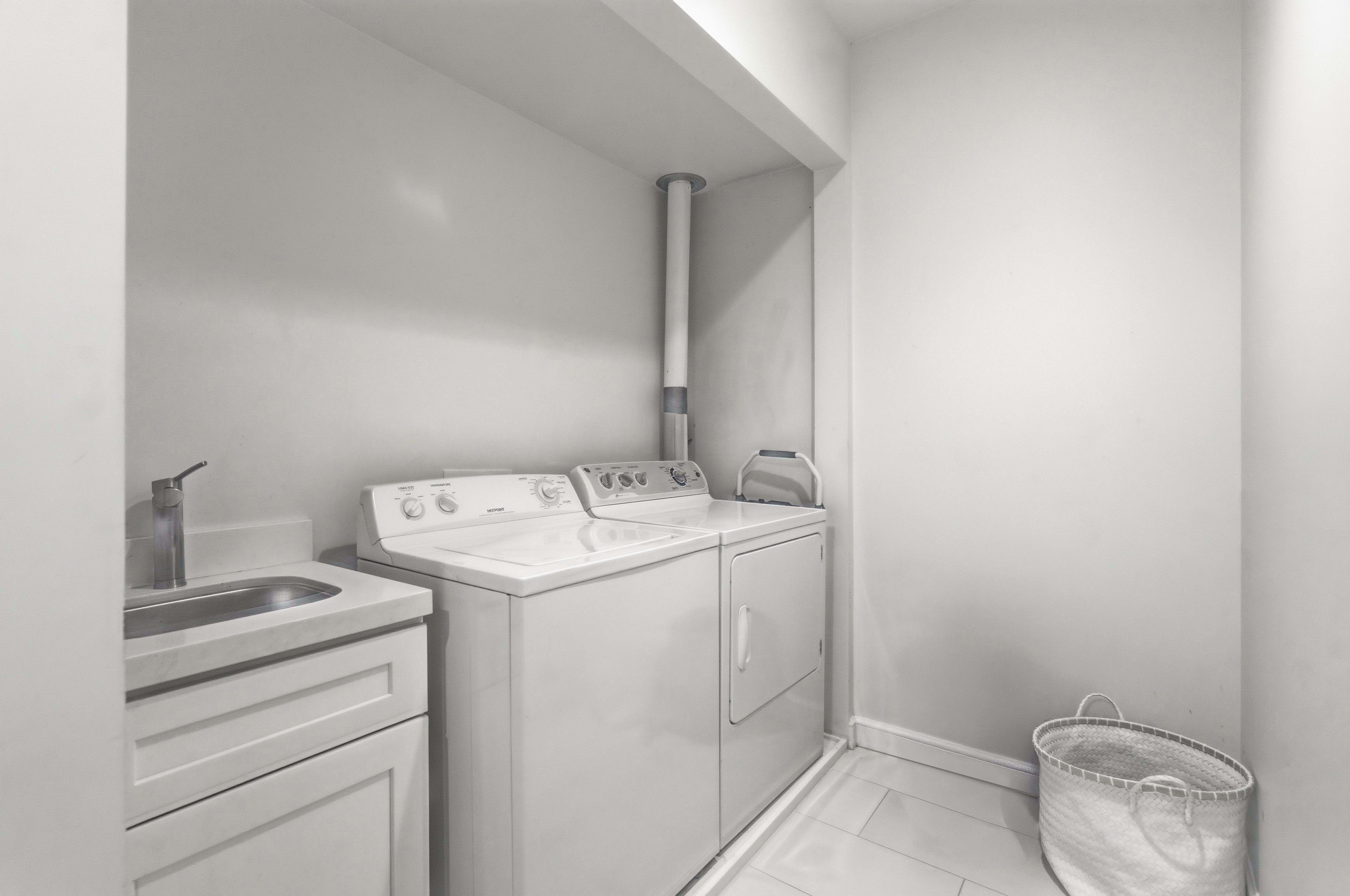 Laundry area with independent washer and dryer and light tile patterned floors