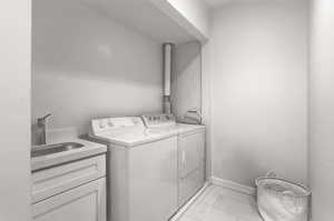 Laundry area with independent washer and dryer and light tile patterned floors