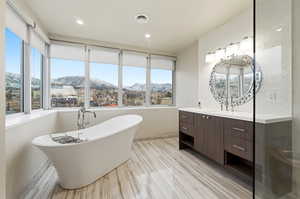 Bathroom with a mountain view, vanity, a soaking tub, and wood finish floors