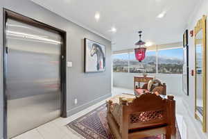 Living area featuring a mountain view, elevator, light tile patterned floors, crown molding, and recessed lighting