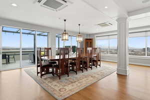 Dining area with light wood finished floors, hanging lights, and ornate columns