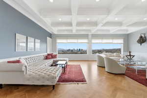 Living room featuring coffered ceiling, parquet floors, a wainscoted wall, recessed lighting, and ornamental molding