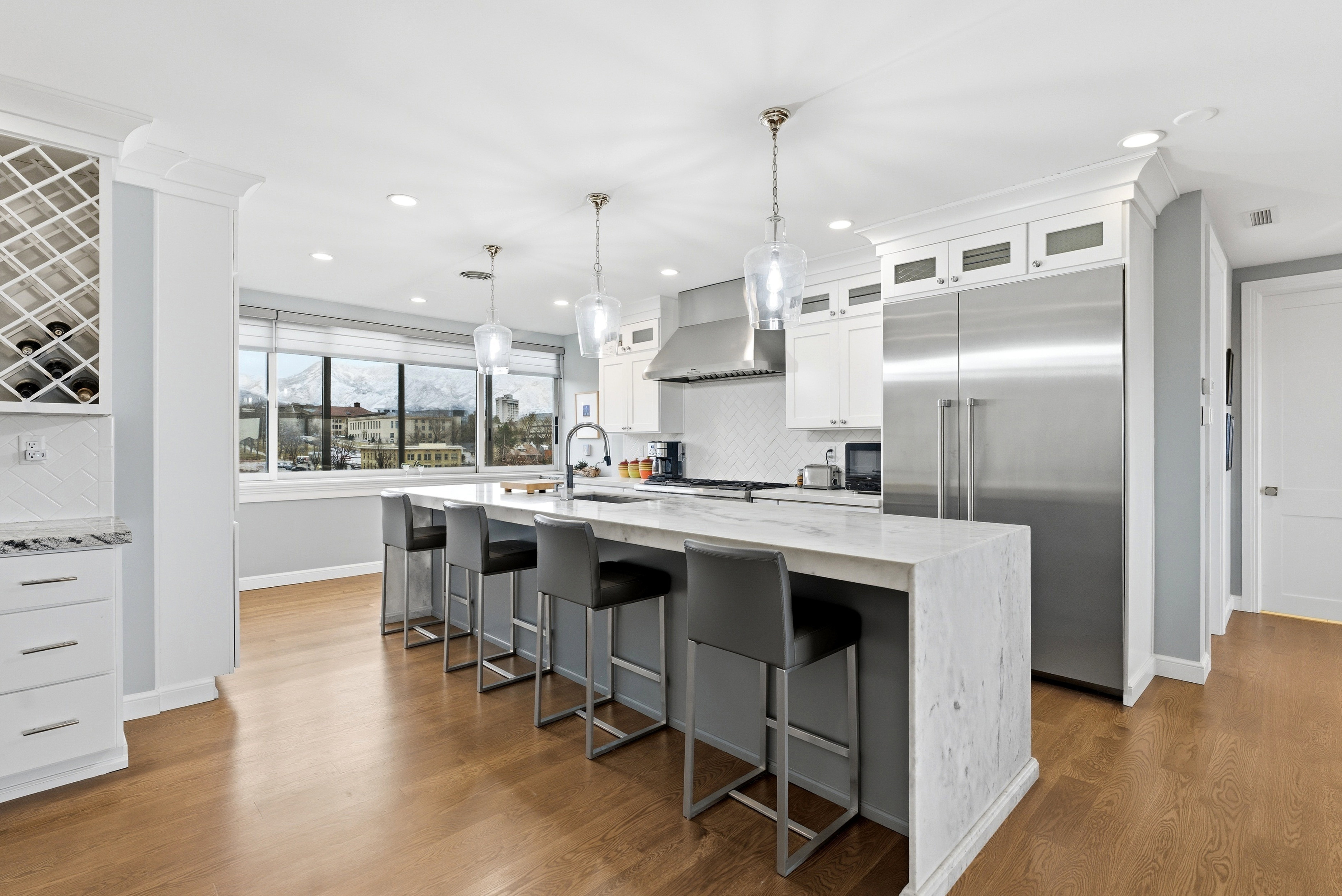 Kitchen with built in fridge, light stone counters, tasteful backsplash, and a kitchen breakfast bar