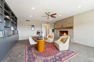 Carpeted living room featuring a tile fireplace, ceiling fan, and recessed lighting