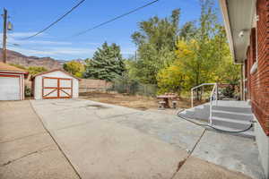 Fenced backyard featuring a detached garage, a patio area, a shed, and a mountain view