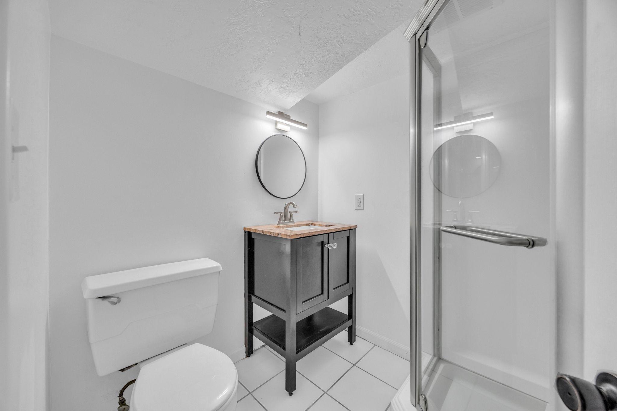 Full bath with a shower stall, vanity, a textured ceiling, and light tile patterned flooring