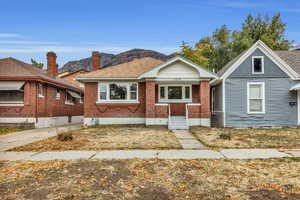 Bungalow featuring a mountain view, brick siding, a shingled roof, and covered porch