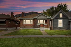 Bungalow featuring a front yard and brick siding