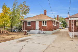Bungalow-style house with a chimney, brick siding, and roof with shingles