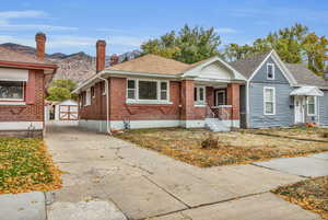 Bungalow with brick siding, roof with shingles, a mountain view, and a storage shed