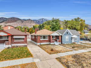 Bungalow-style home featuring brick siding, a chimney, a shingled roof, a mountain view, and driveway