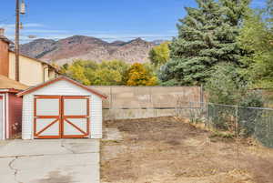 Fenced backyard featuring a mountain view and a shed