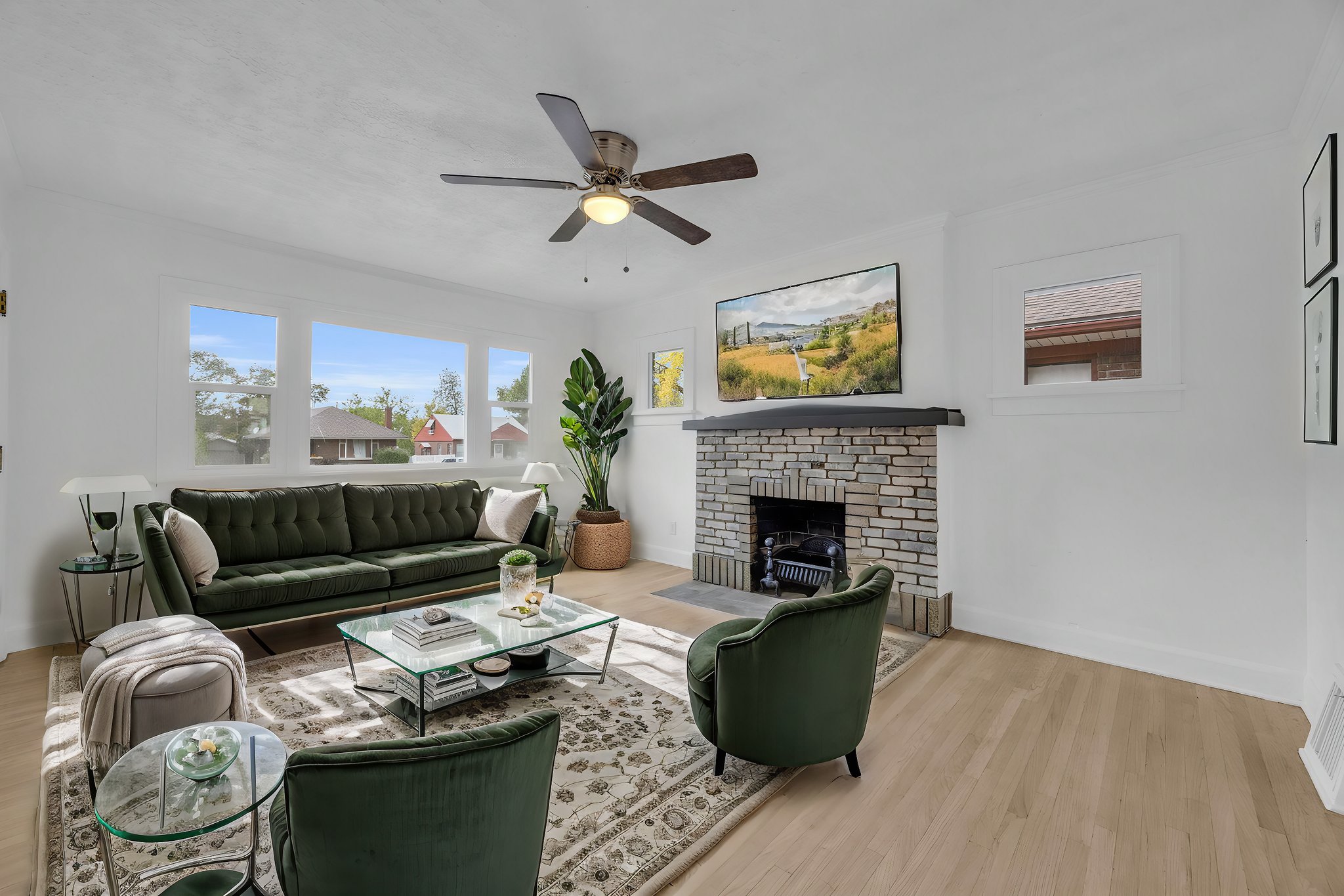 Living area featuring light wood finished floors, ceiling fan, and a fireplace