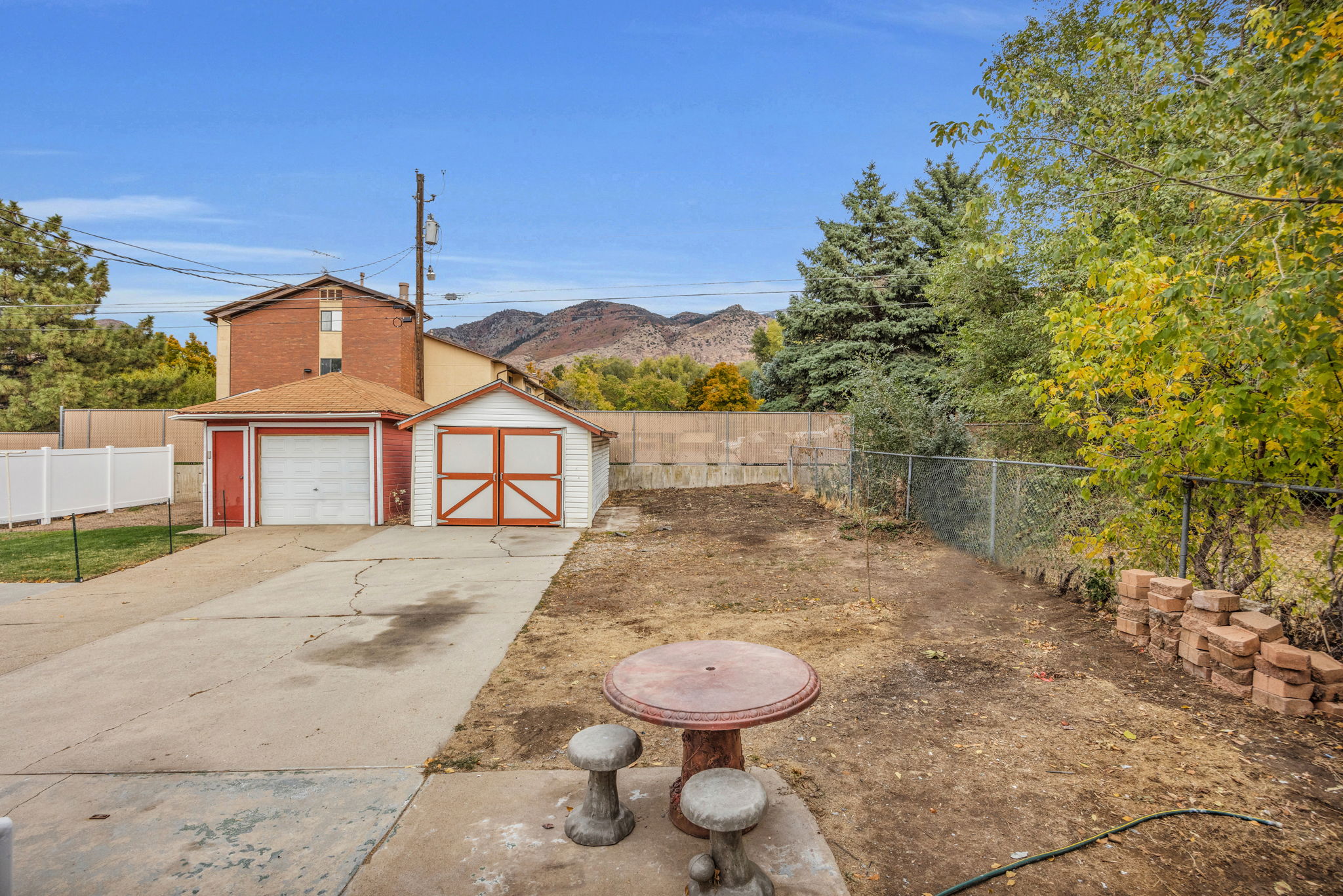 Fenced backyard with a mountain view, an outdoor structure, a garage, and concrete driveway