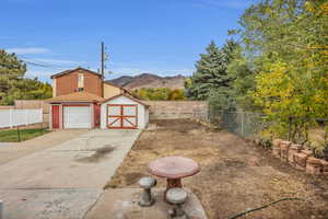 Fenced backyard with a mountain view, an outdoor structure, a garage, and concrete driveway