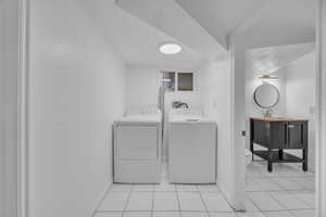 Laundry area featuring washing machine and dryer and light tile patterned flooring