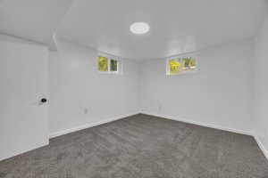 Below grade area featuring dark carpet and baseboards