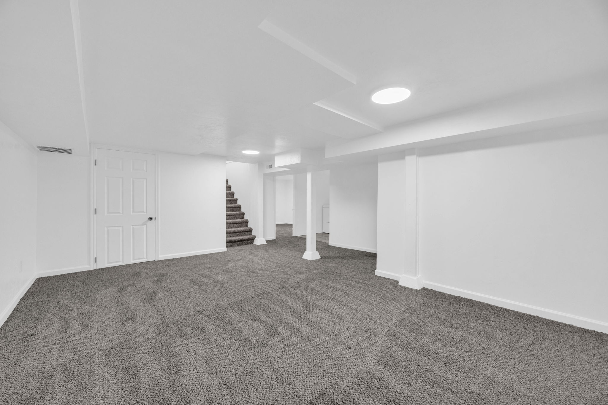 Finished below grade area featuring stairway and dark colored carpet