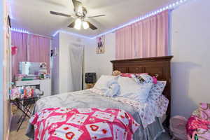 Carpeted bedroom with ceiling fan and a textured ceiling