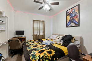 Bedroom with an office area, ceiling fan, and carpet