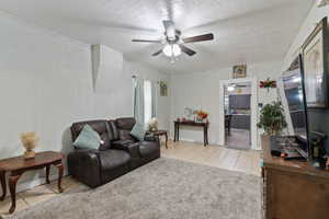 Living area featuring a textured ceiling, ceiling fan, and light tile patterned flooring