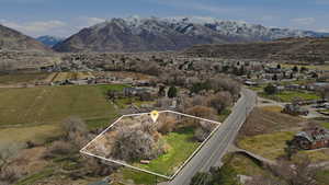 Overview of rural landscape featuring property parcel outlined, mountains, and nearby suburban area