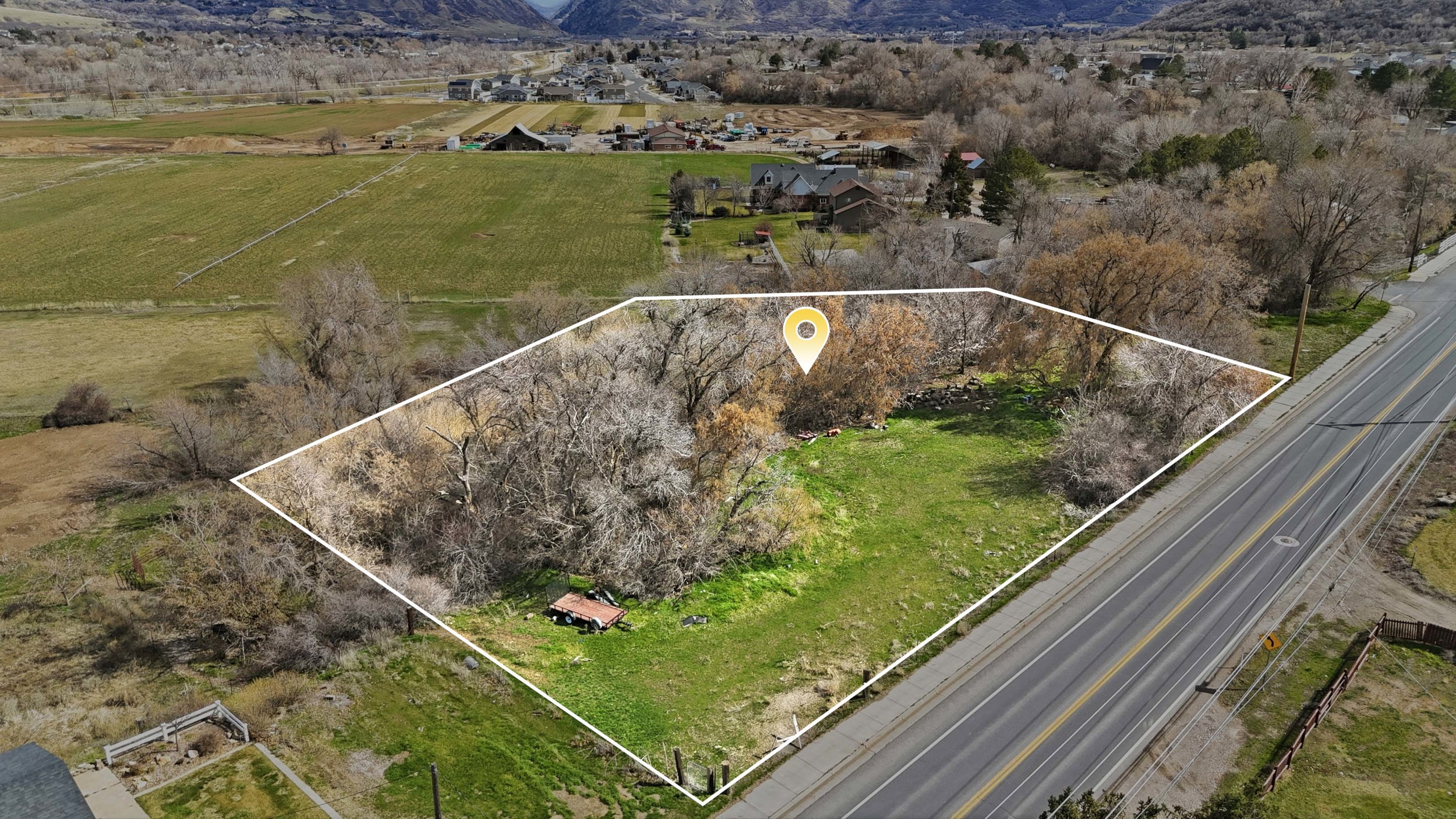 Overview of rural landscape with property parcel outlined and a mountainous background