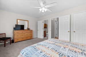 Bedroom featuring light carpet, ceiling fan, and connected bathroom
