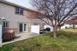 Rear view of house with stucco siding, a patio, and stone siding