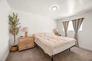 Carpeted bedroom featuring baseboards and a textured ceiling