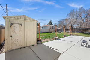 Fenced backyard featuring a storage unit and a patio