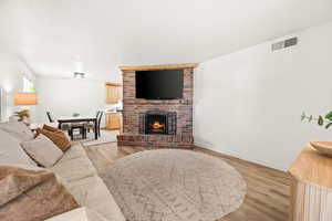 Living room with light wood-type flooring and a brick fireplace