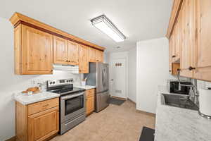 Kitchen with stainless steel appliances, light countertops, light wood finish cabinets, and light flooring